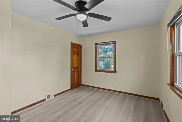 an empty room with wooden floor chandelier fan and windows