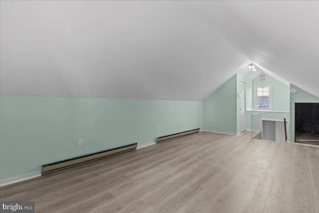 an empty room with wooden floor fireplace and windows