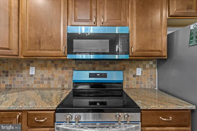 a kitchen with granite countertop wood cabinets and a stove top oven