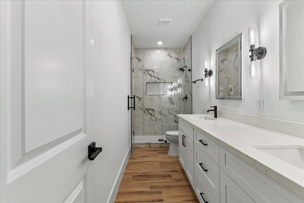 8323 Observatory Street, Unit A/B Houston, TX 77088 - Photo 27 of 38 Unit B - Stylish primary bath is equipped with dual vanities, LED mirrors, and walk-in shower with ceramic tile surround.