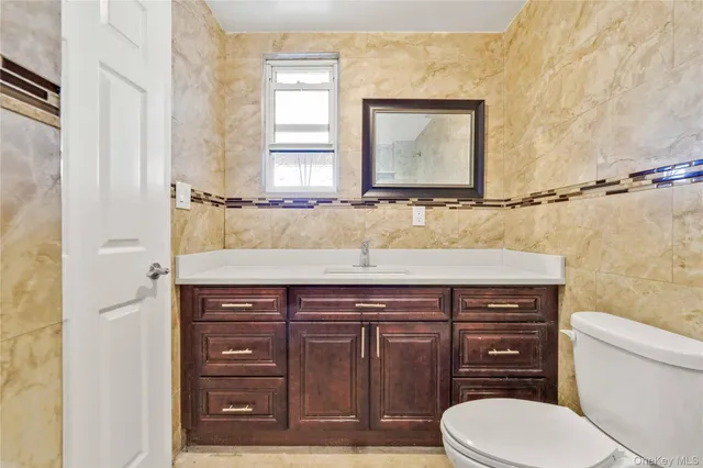 a bathroom with a granite countertop toilet sink and mirror