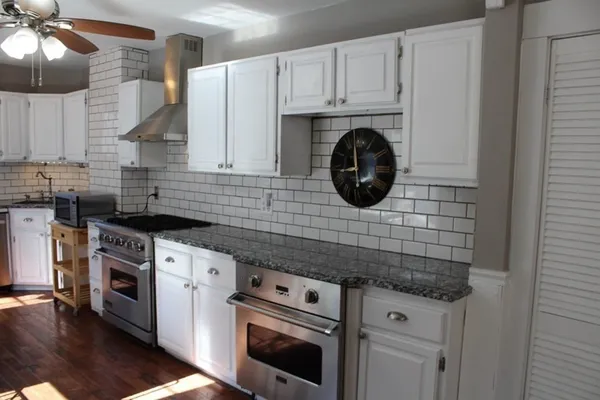 a kitchen with granite countertop a sink a stove and cabinets
