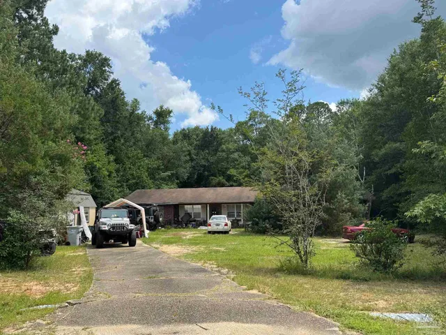 a front view of a house with a garden and trees