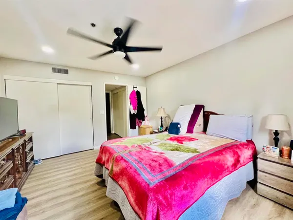 a bedroom with a bed a dresser and a chandelier