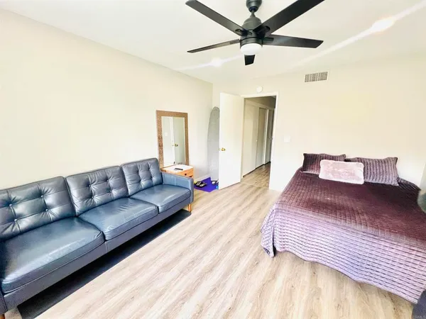 a spacious bedroom with a bed couch and a ceiling fan