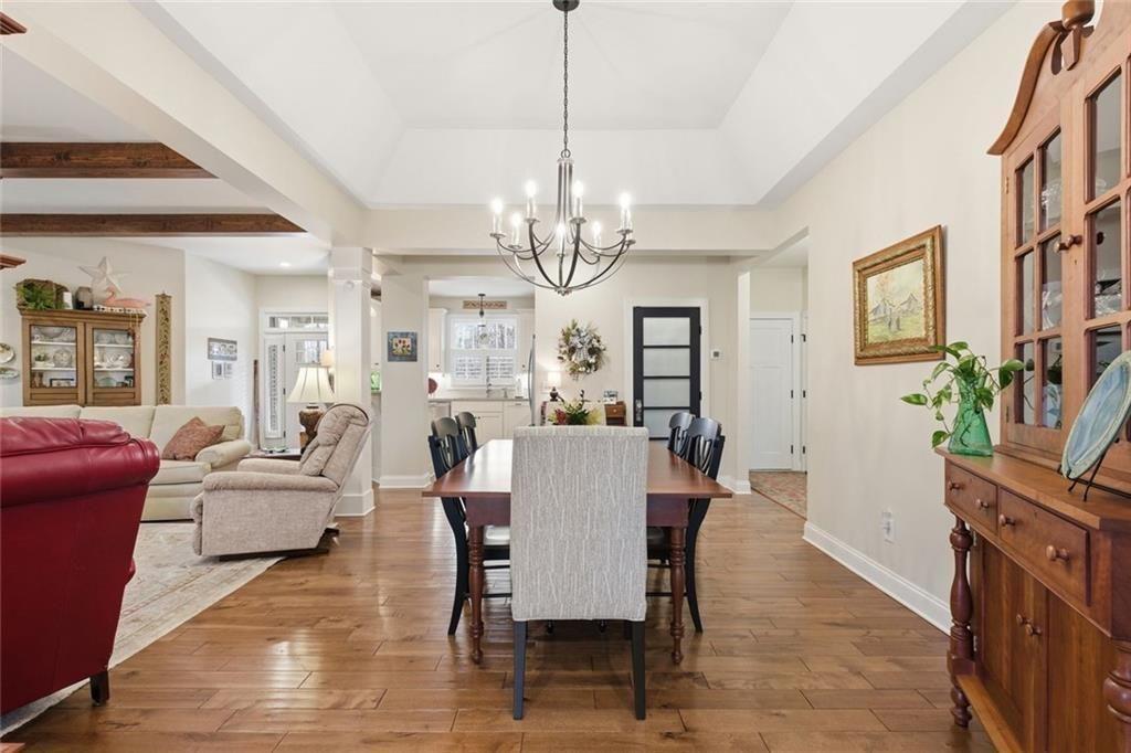 7671 Fern Lane Lula, GA 30554 - Photo 14 of 67 a dining room with wooden floor a chandelier a glass table and chairs