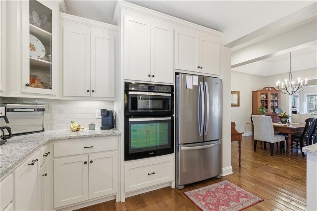 7671 Fern Lane Lula, GA 30554 - Photo 18 of 67 a kitchen with granite countertop a refrigerator stove and white cabinets