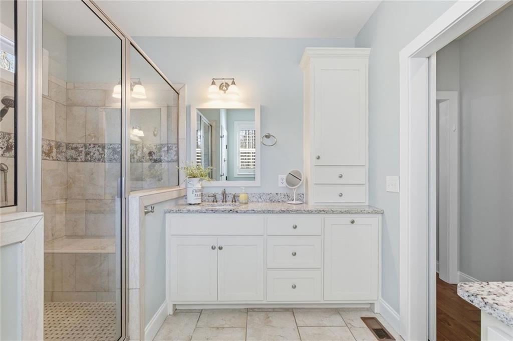 7671 Fern Lane Lula, GA 30554 - Photo 28 of 67 a bathroom with a granite countertop sink a mirror and a shower