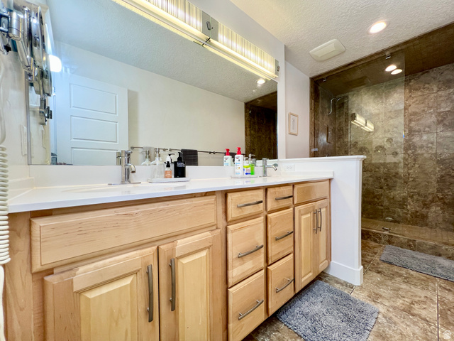 1017 South 275 West Logan, UT 84321 - Photo 13 of 36 Full bath with double vanity, walk in shower, a textured ceiling, and recessed lighting