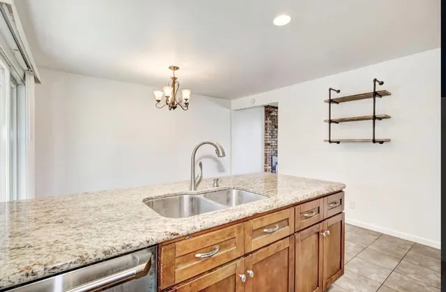 a kitchen with stainless steel appliances kitchen island granite countertop a refrigerator a stove a sink dishwasher and white cabinets with wooden floor