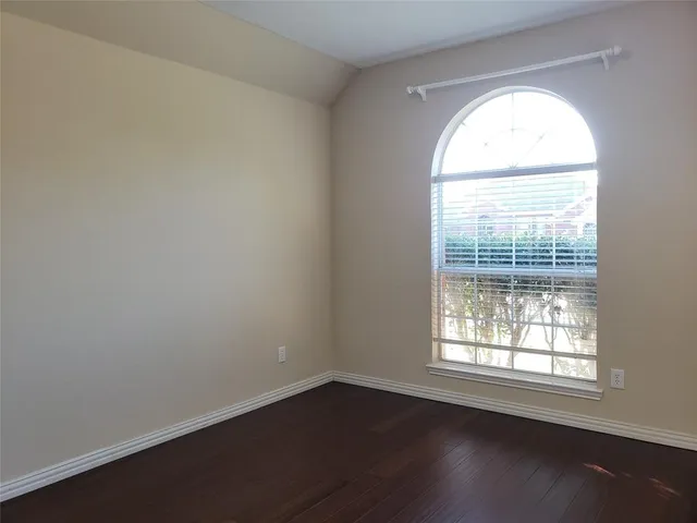 an empty room with wooden floor and a window