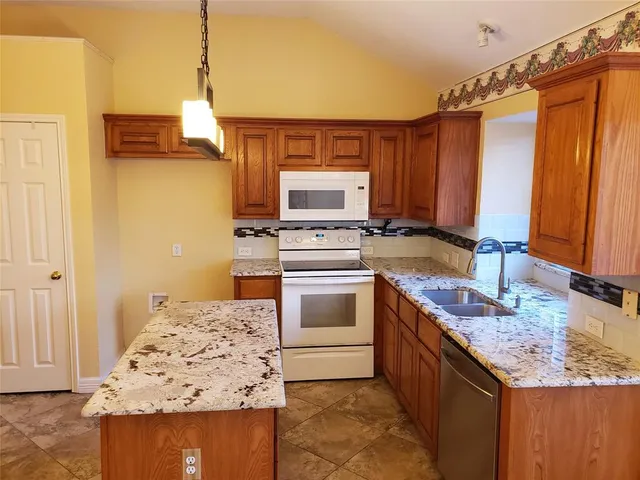 a kitchen with stainless steel appliances granite countertop a stove a sink and a refrigerator