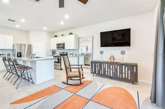 a kitchen with stainless steel appliances granite countertop a stove a sink a refrigerator a microwave oven with a dining table and chairs