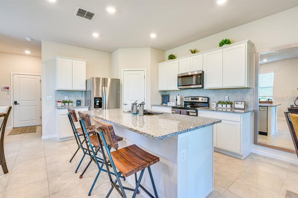 5443 Elmview Crossing Wesley Chapel, FL 33545 - Photo 10 of 41 a kitchen with stainless steel appliances granite countertop a stove a sink a refrigerator a microwave oven with a dining table and chairs