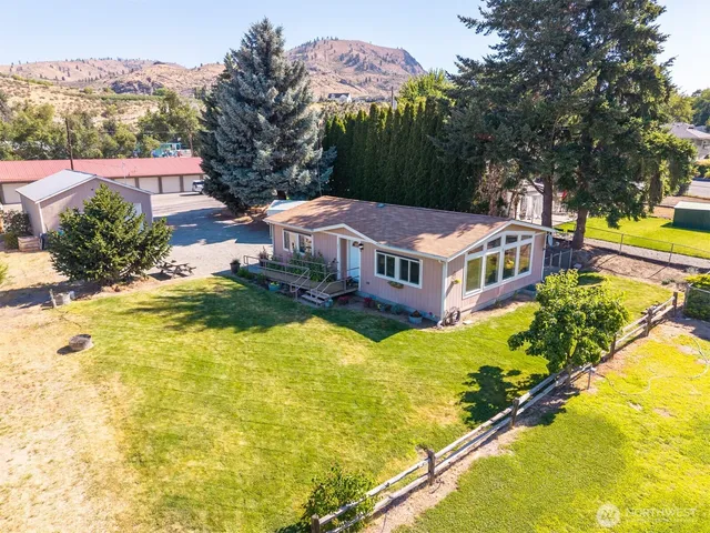 a aerial view of a house with swimming pool lawn chairs and large trees