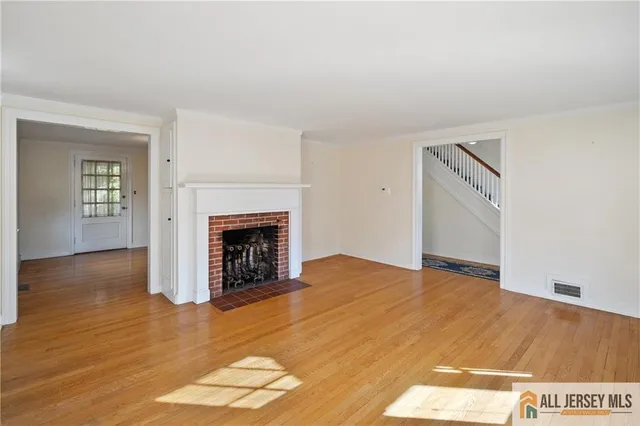 a view of an empty room with wooden floor and a fireplace