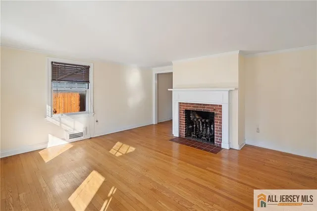a view of an empty room with wooden floor and a fireplace