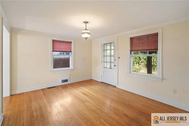 an empty room with wooden floor chandelier and windows