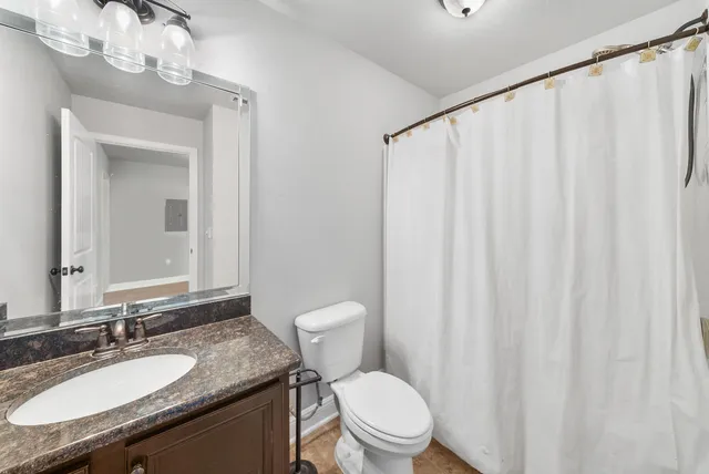 a bathroom with a granite countertop sink toilet and mirror