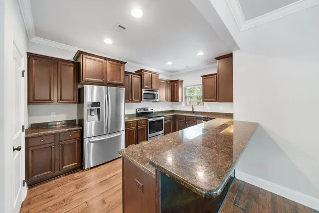 a kitchen with stainless steel appliances granite countertop a refrigerator a stove top oven a sink and dishwasher