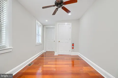 a view of empty room with wooden floor and fan