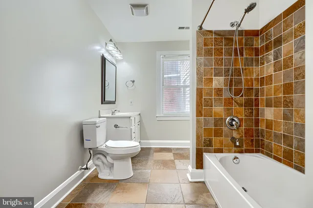 a bathroom with a sink a toilet a mirror a bathtub and shower