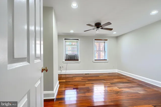 a view of empty room with wooden floor and fan