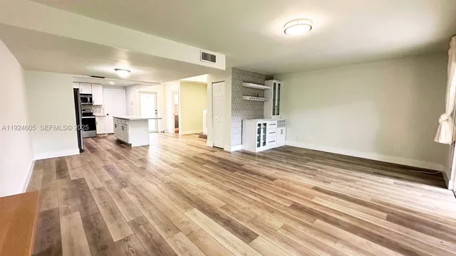 a view of a living room with kitchen island stainless steel appliances wooden floor and view living room