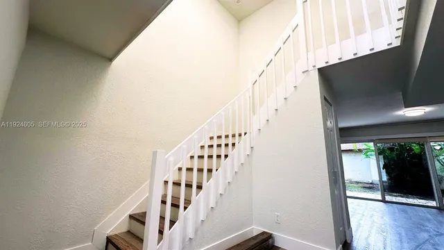 a view of staircase with wooden floor and white walls