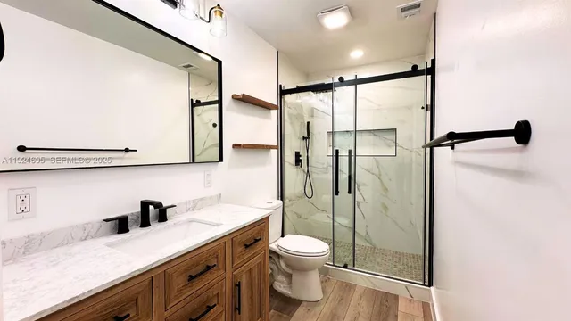 a bathroom with a granite countertop sink mirror shower and toilet