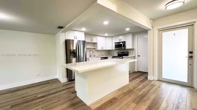 a kitchen with refrigerator cabinets and wooden floor