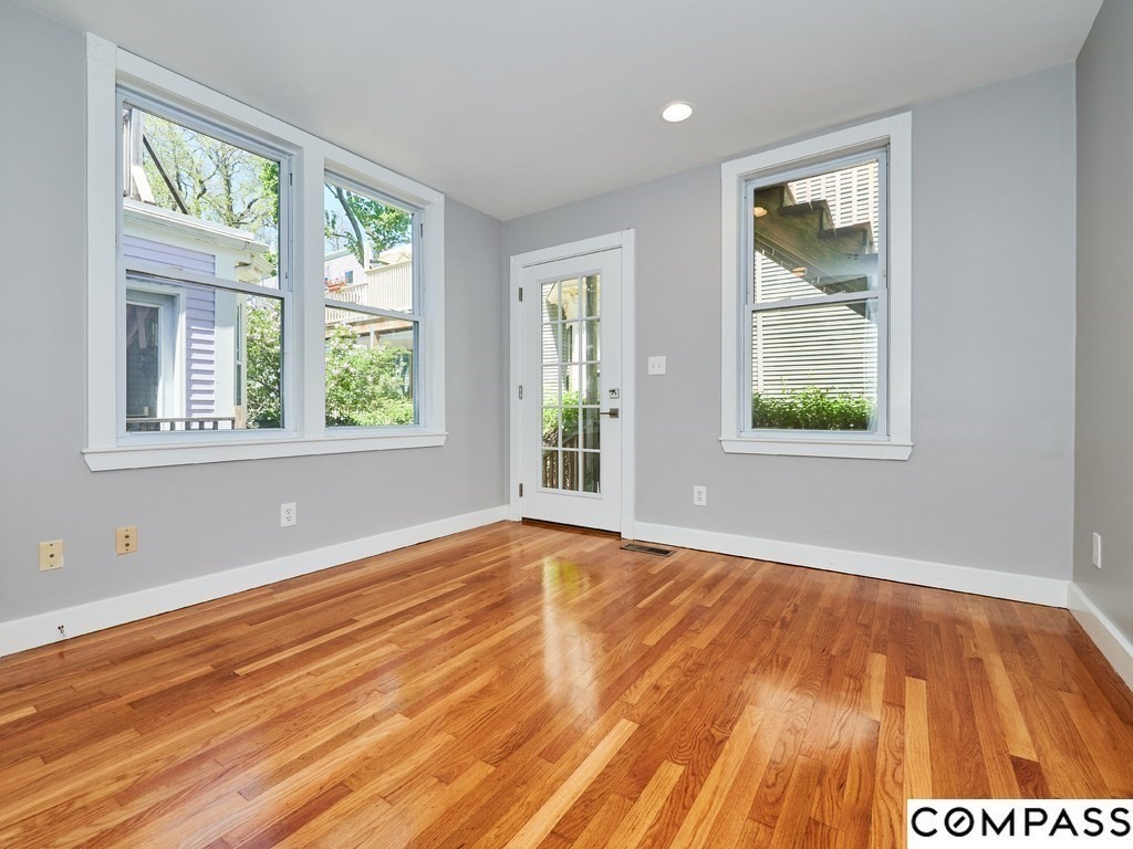 145 Pearl Street, Unit 145 Cambridge, MA 02139 - Photo 13 of 26 a view of an empty room with wooden floor and a window
