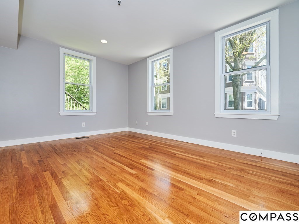 145 Pearl Street, Unit 145 Cambridge, MA 02139 - Photo 9 of 26 a view of an empty room with wooden floor and a window
