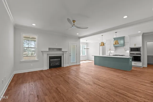 a view of an empty room with wooden floor fireplace and a window