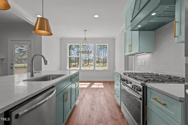 a kitchen with stainless steel appliances granite countertop a sink a stove a refrigerator and island with wooden floor