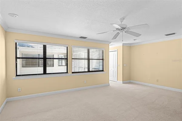 an empty room with chandelier fan and windows