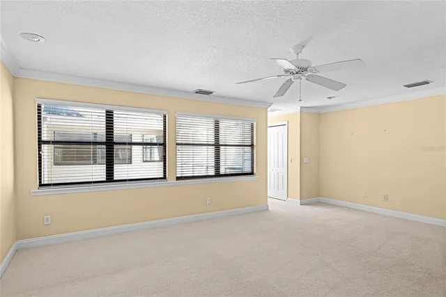 an empty room with chandelier fan and windows