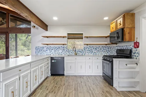 a large white kitchen with stainless steel appliances kitchen island granite countertop a large counter top and white cabinets