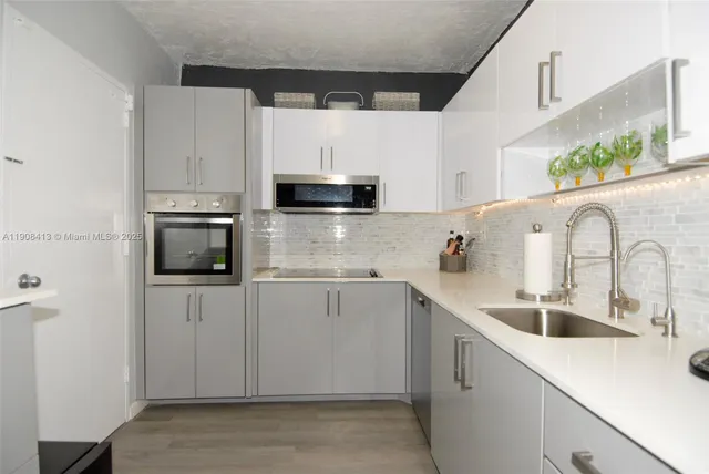 a kitchen with stainless steel appliances a sink a stove a microwave a refrigerator a sink and cabinets