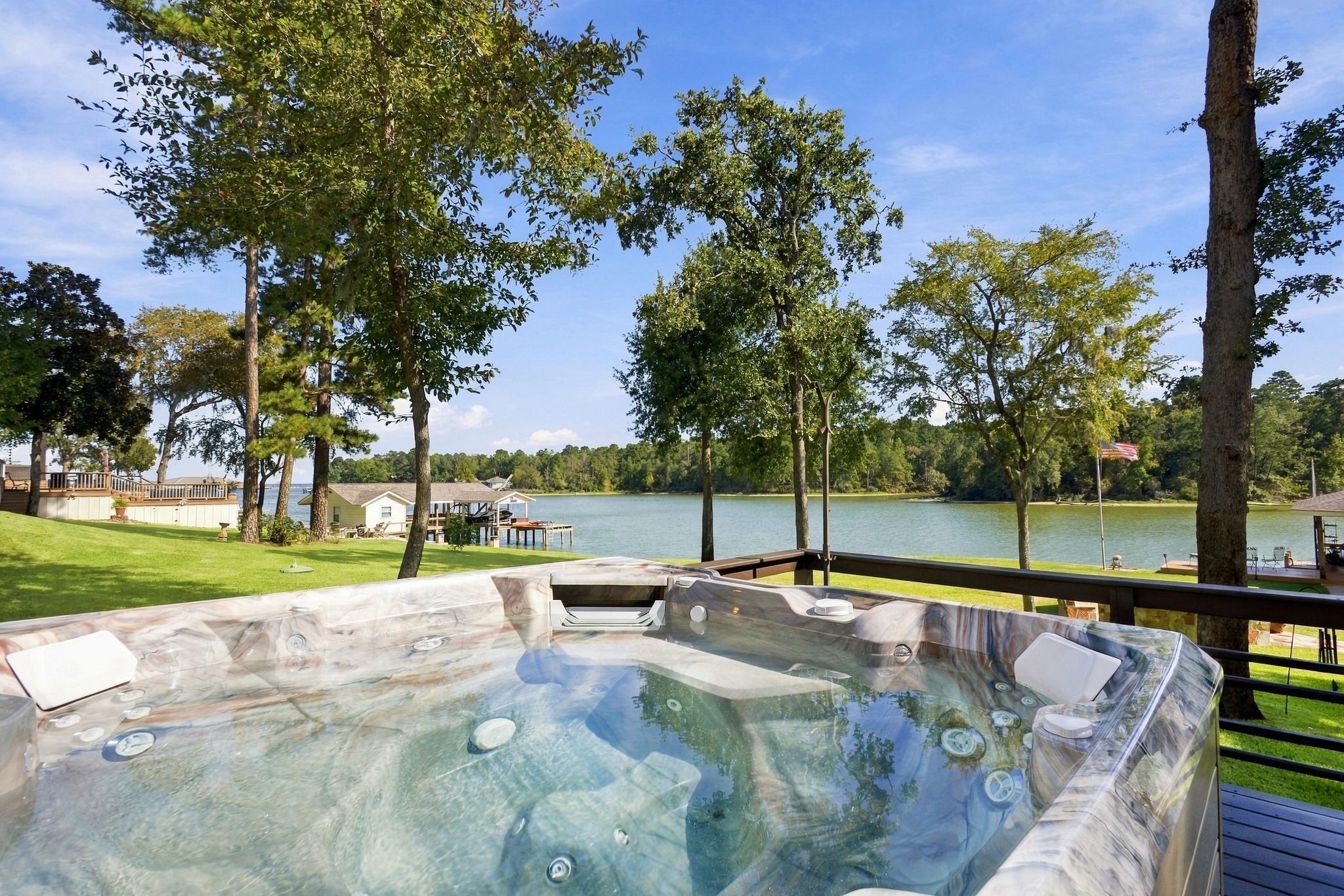20341 Bay Hill Road Point Blank, TX 77364 - Photo 34 of 50 Relax in the luxurious hot tub on the deck, offering stunning views of the serene lake and lush greenery.