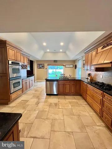 a large kitchen with stainless steel appliances granite countertop a large stove top oven and cabinets