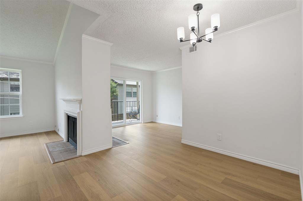 5300 Keller Springs Road, Unit 2042 Dallas, TX 75248 - Photo 3 of 28 Open living area featuring wood-finish flooring, a white mantel fireplace, crown molding, and a modern chandelier