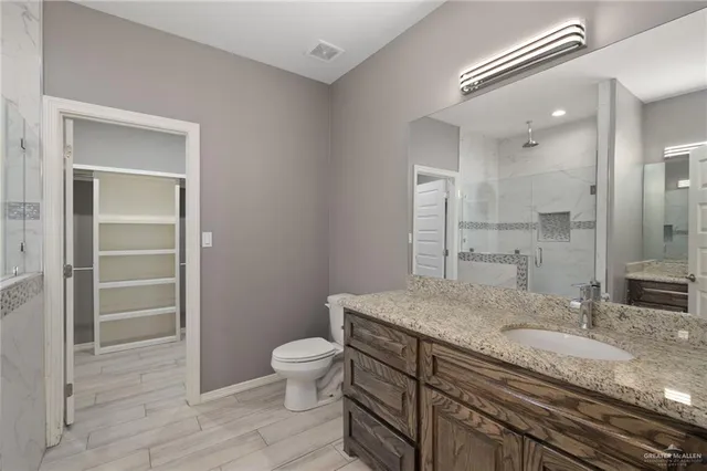 a bathroom with a granite countertop sink a toilet and shower