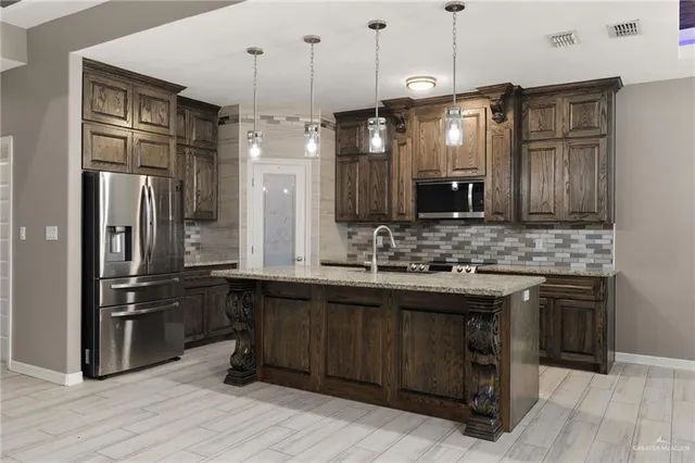 a kitchen with stainless steel appliances granite countertop a sink a stove a refrigerator and a wooden floor
