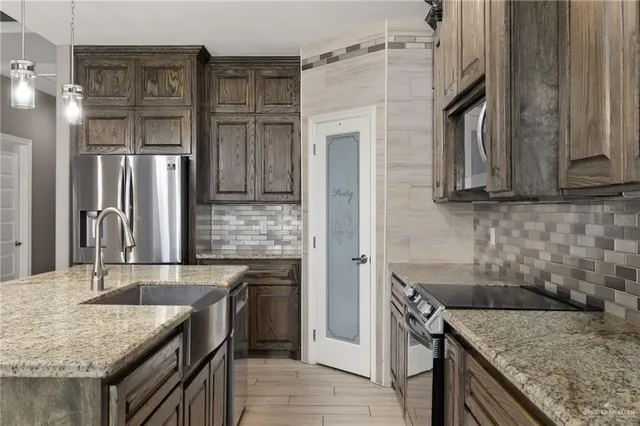a kitchen with stainless steel appliances granite countertop a sink stove and refrigerator
