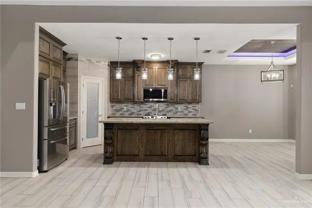 a view of kitchen with granite countertop cabinets and refrigerator