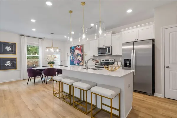 a kitchen with stainless steel appliances granite countertop a refrigerator a stove a sink dishwasher a dining table and chairs with wooden floor