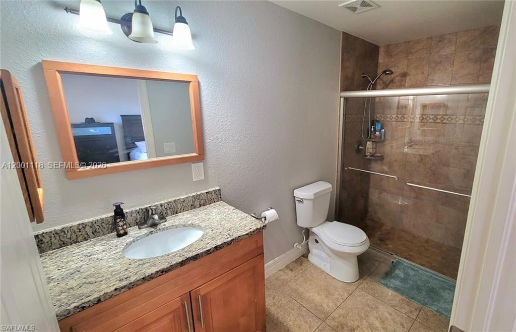 152 Pullman Street, Unit 152 Lehigh Acres, FL 33974 - Photo 13 of 15 a bathroom with a granite countertop sink a toilet and a mirror