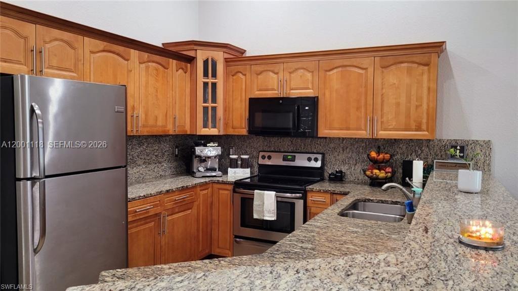 152 Pullman Street, Unit 152 Lehigh Acres, FL 33974 - Photo 5 of 15 a kitchen with stainless steel appliances granite countertop a refrigerator stove top oven a sink and dishwasher