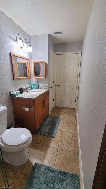 152 Pullman Street, Unit 152 Lehigh Acres, FL 33974 - Photo 9 of 15 a bathroom with a granite countertop toilet sink and mirror